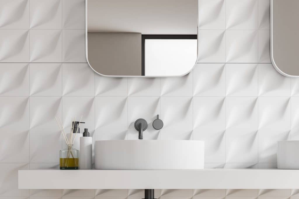 Close up of bathroom sink standing on white countertop with vertical mirror in room with white tiled walls. 3d rendering